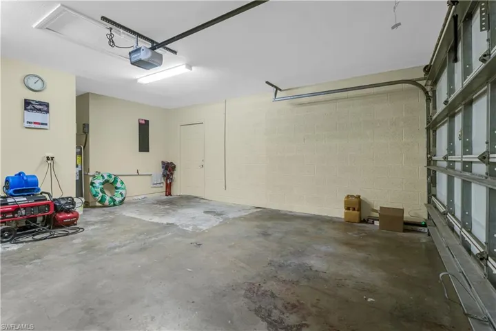 Spacious garage featuring a concrete floor, painted block walls, and a white ceiling with fluorescent lighting