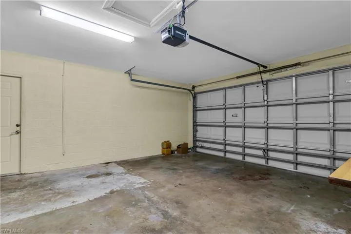 Spacious two-car garage featuring a concrete floor, painted block walls, and overhead fluorescent lighting