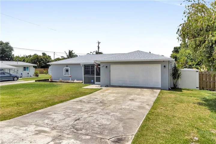 Single-story residence featuring a two-car garage with a white panel door, screened-in front entry, and a concrete driveway