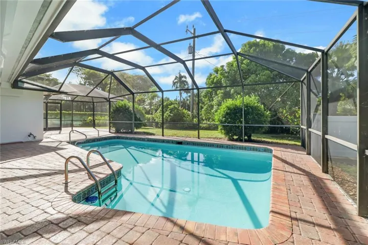Outdoor pool featuring a patio, a sunroom, and glass enclosure