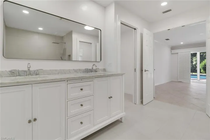 Full bathroom featuring double vanity, a tile shower, recessed lighting, and light tile patterned floors