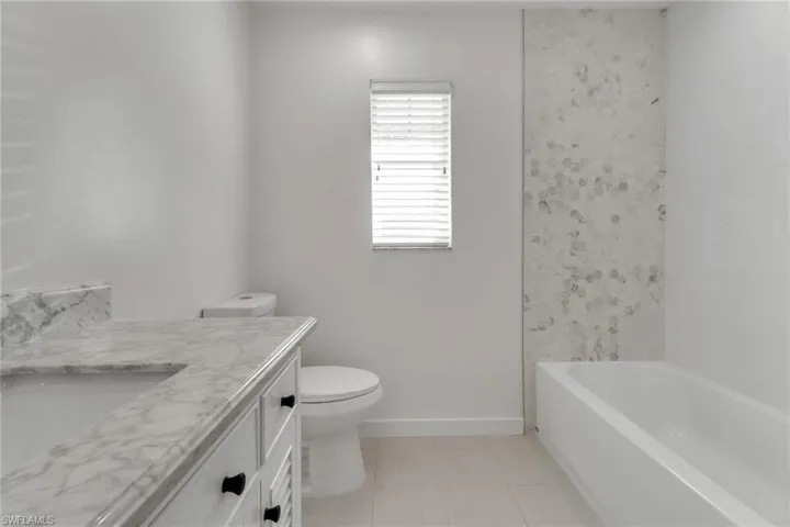 Bathroom featuring vanity, light tile patterned floors, and tub / shower combination