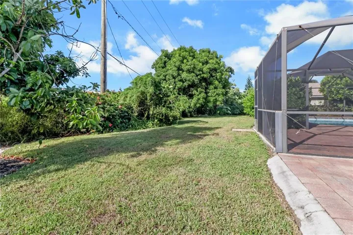 View of grassy yard featuring glass enclosure and a sunroom