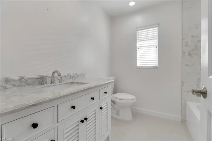 Bathroom with vanity, light tile patterned flooring, bathing tub / shower combination, and recessed lighting