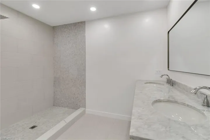 Bathroom featuring a stall shower, double vanity, recessed lighting, and light tile patterned floors