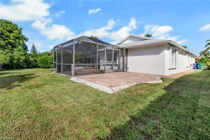 Back of property featuring a lanai, a sunroom, stucco siding, and a lawn