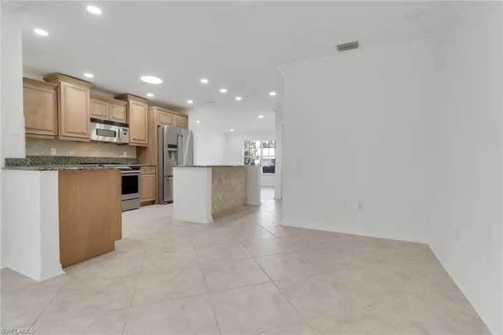 Kitchen with a kitchen island, stainless steel appliances, light tile patterned flooring, recessed lighting, and dark stone counters