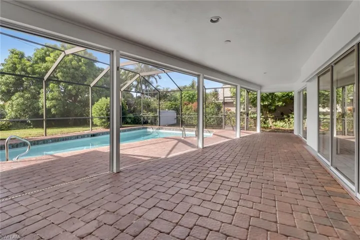 Swimming pool featuring a patio area, a sunroom, and a lanai