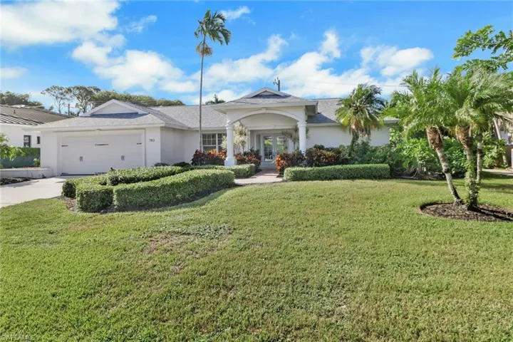View of front of property with french doors, a front yard, stucco siding, an attached garage, and driveway