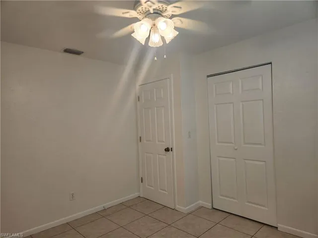 Unfurnished bedroom with light tile patterned floors, a ceiling fan, and a closet