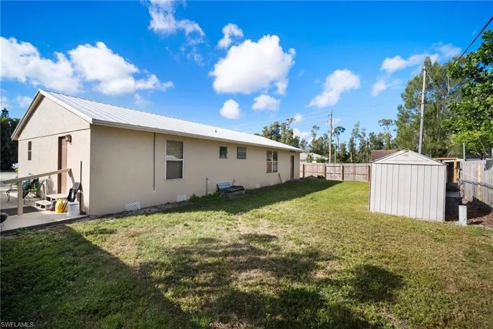 Rear view of house with a patio, a lawn, and a storage unit