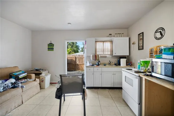Kitchen featuring light tile patterned floors, white range with electric stovetop, sink, and white cabinets