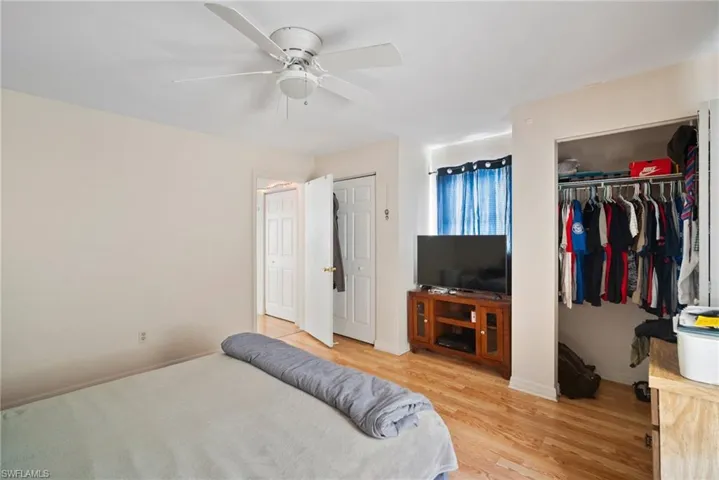 Bedroom with multiple closets, hardwood / wood-style floors, and ceiling fan