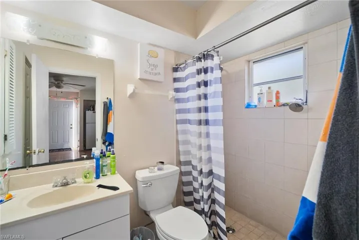 Bathroom with vanity, toilet, and curtained shower