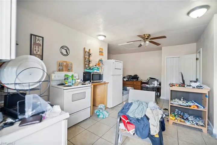 Kitchen featuring light tile patterned floors, white cabinets, and white appliances