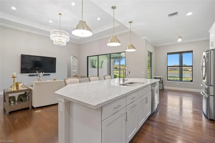 Kitchen featuring stainless steel appliances, a kitchen island with sink, sink, pendant lighting, and white cabinets