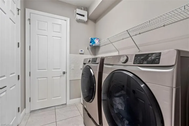 Laundry area with light tile patterned floors and independent washer and dryer