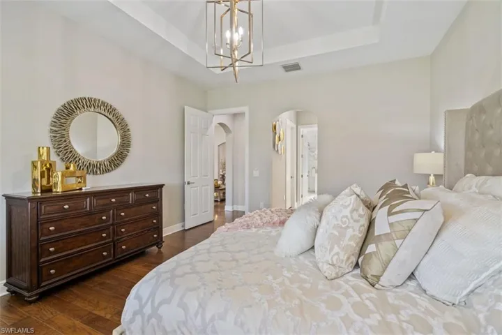 Bedroom featuring a raised ceiling, dark hardwood / wood-style flooring, and a chandelier