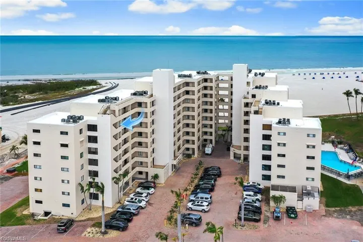 Aerial view of apartment complex and waterfront with a beach
