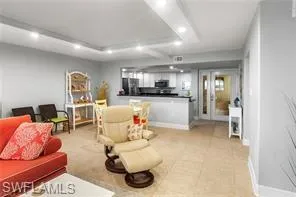 Living room featuring a tray ceiling, recessed lighting, and light tile patterned floors