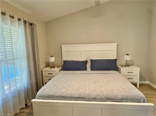 Bedroom with vaulted ceiling and light wood-style floors