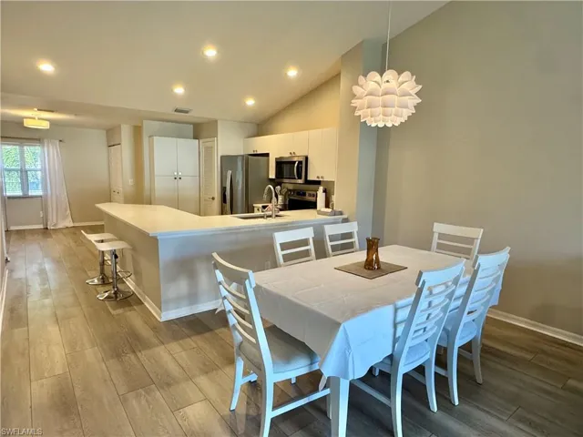 Dining area with light wood-type flooring, high vaulted ceiling, recessed lighting, and a chandelier