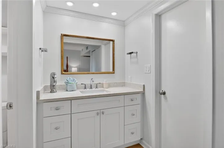 Bathroom with vanity, ornamental molding, and recessed lighting
