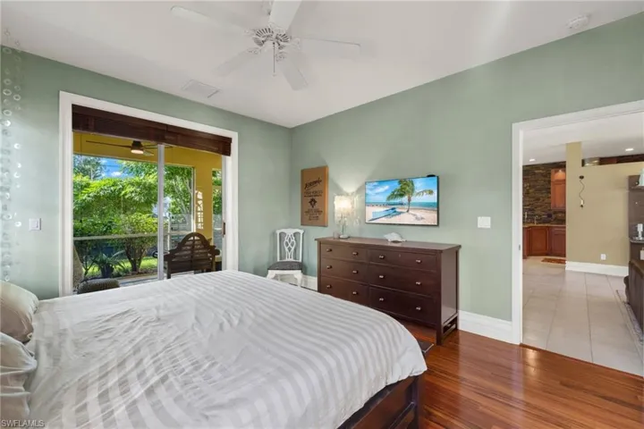 Tiled bedroom featuring access to outside, ensuite bathroom, and ceiling fan