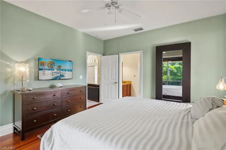 Bedroom featuring access to exterior, ensuite bathroom, ceiling fan, and dark hardwood / wood-style flooring
