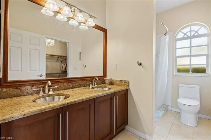 Bathroom with double vanity, tile patterned floors, and toilet