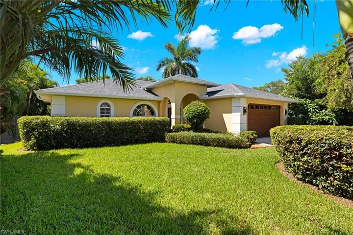 View of front of property with a garage and a front lawn