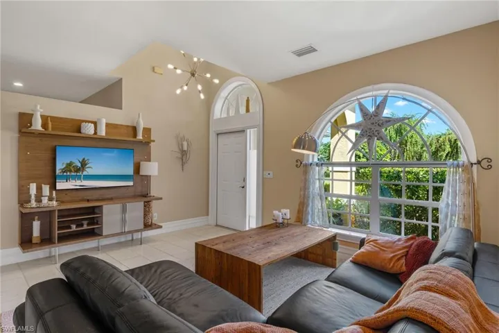 Living room with a notable chandelier, light tile patterned flooring, and lofted ceiling