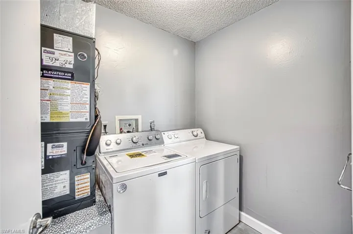 Laundry room featuring a textured ceiling, heating unit, and washer and clothes dryer