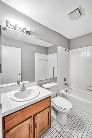 Bathroom with vanity, bathtub / shower combination, and light tile patterned floors