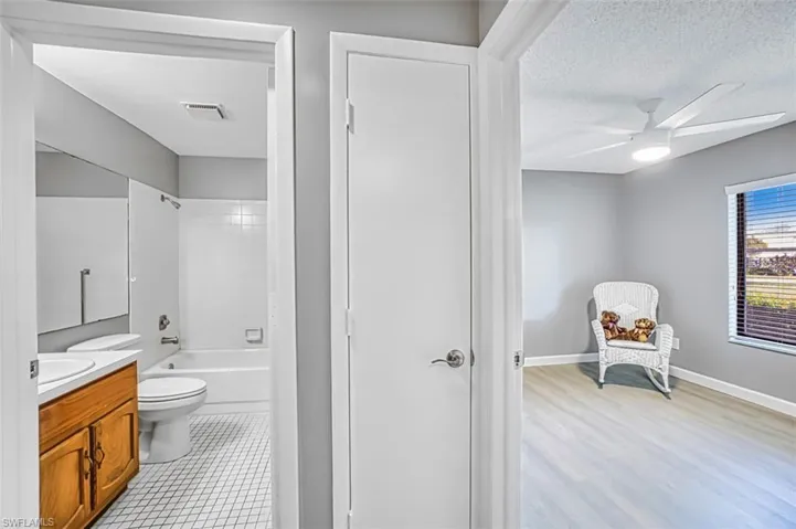 Full bathroom featuring vanity, shower / washtub combination, a textured ceiling, and ceiling fan