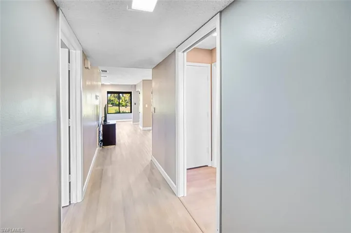 Hall with light wood-type flooring and a textured ceiling