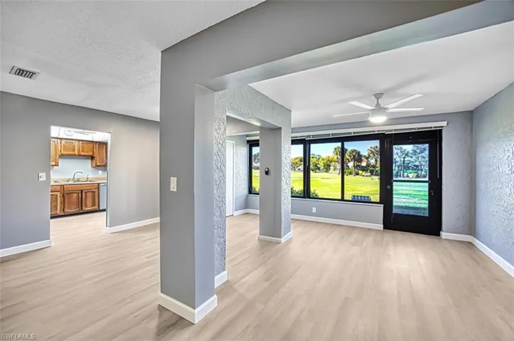 Unfurnished living room with a ceiling fan, light wood finished floors, a textured ceiling, and a textured wall