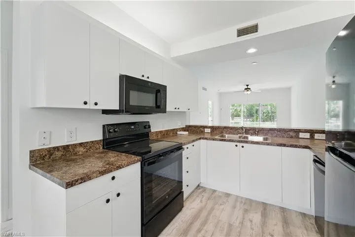 Kitchen featuring black appliances, ceiling fan, light wood-type flooring, white cabinets, and recessed lighting