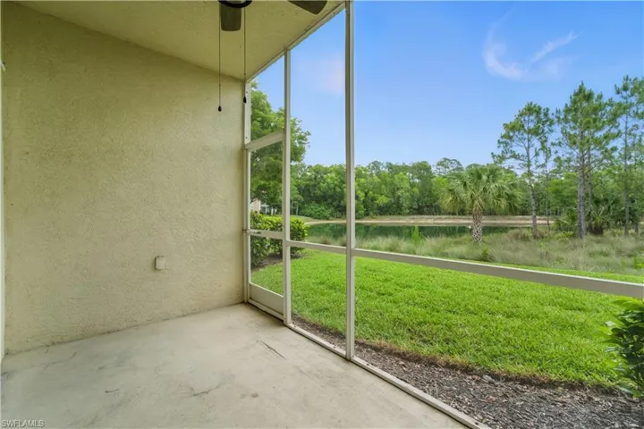 Unfurnished sunroom featuring ceiling fan, view of wooded area, and a water view