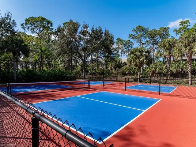 View of tennis court with community basketball court and view of wooded area