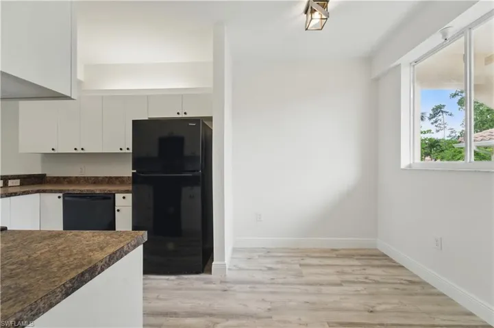 Kitchen featuring black appliances, dark countertops, white cabinets, and light wood-type flooring