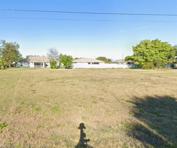 Expansive unimproved land featuring mature trees and a clear sky