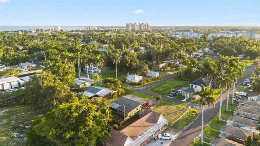 Aerial view of property and surrounding area featuring a tree filled landscape and nearby suburban area