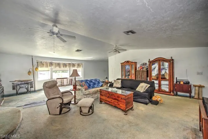 Carpeted living room featuring lofted ceiling and ceiling fan
