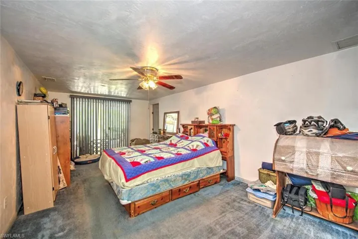 Carpeted bedroom with a textured ceiling and ceiling fan