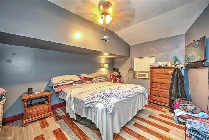 Bedroom with lofted ceiling, hardwood / wood-style floors, and ceiling fan
