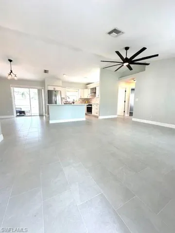 Unfurnished living room with a ceiling fan, light tile patterned floors, baseboards, and visible vents