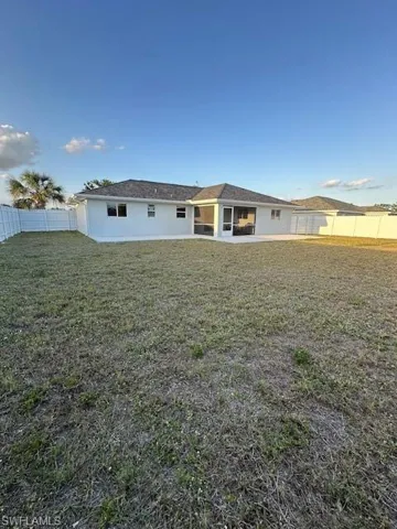 Rear view of property with a lawn, a fenced backyard, and stucco siding