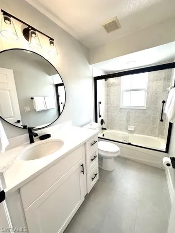Guest Full bathroom with vanity, toilet, tile patterned floors, visible vents, and combined bath / shower with glass door