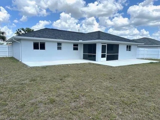 Back of property with a patio, stucco siding, fence, and a yard